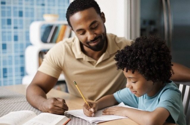 Father helping son (7-9) with homework --- Image by © Tim Pannell/Corbis